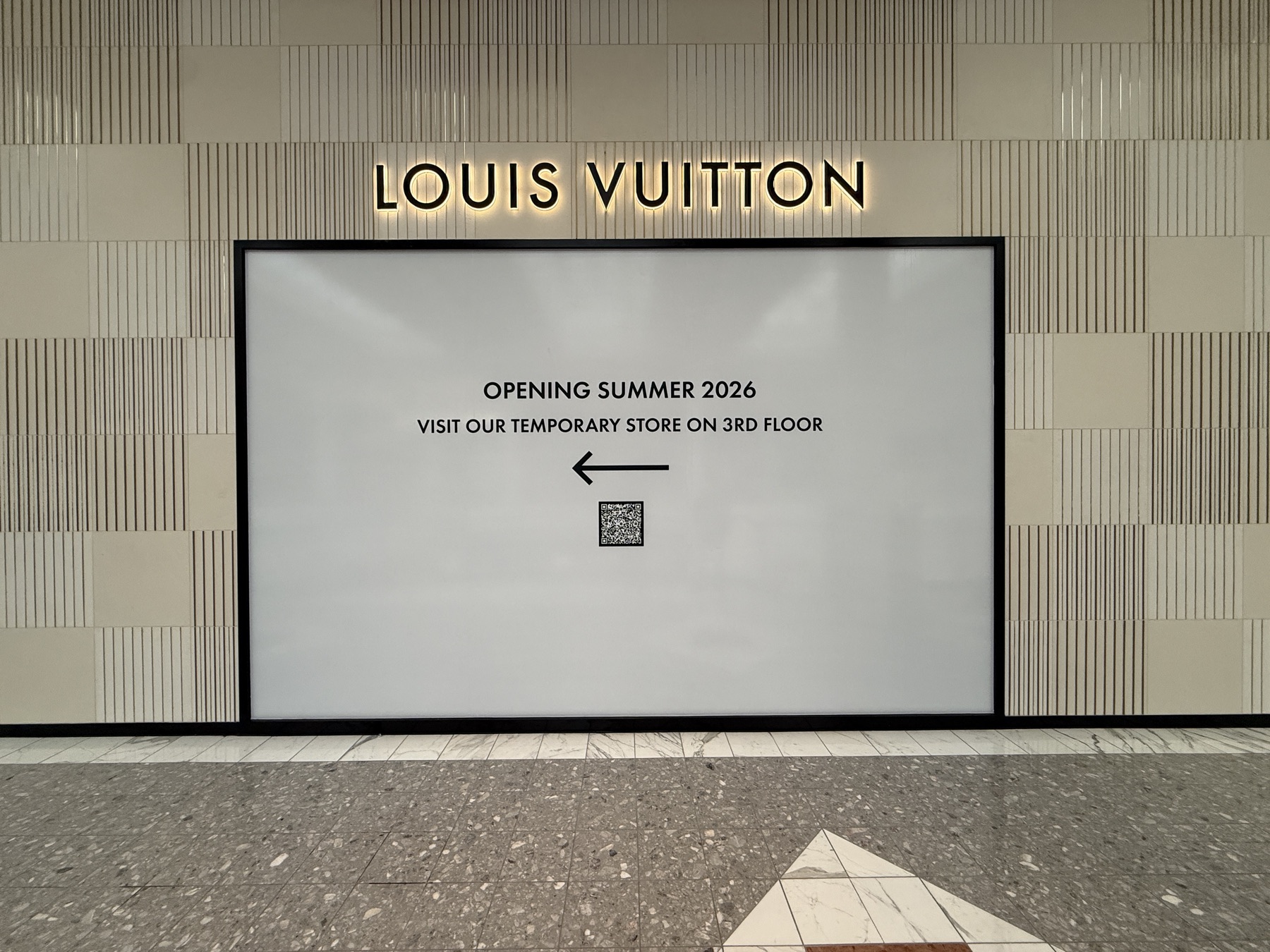 Backlit construction barricade with dimensional letters at a mall storefront