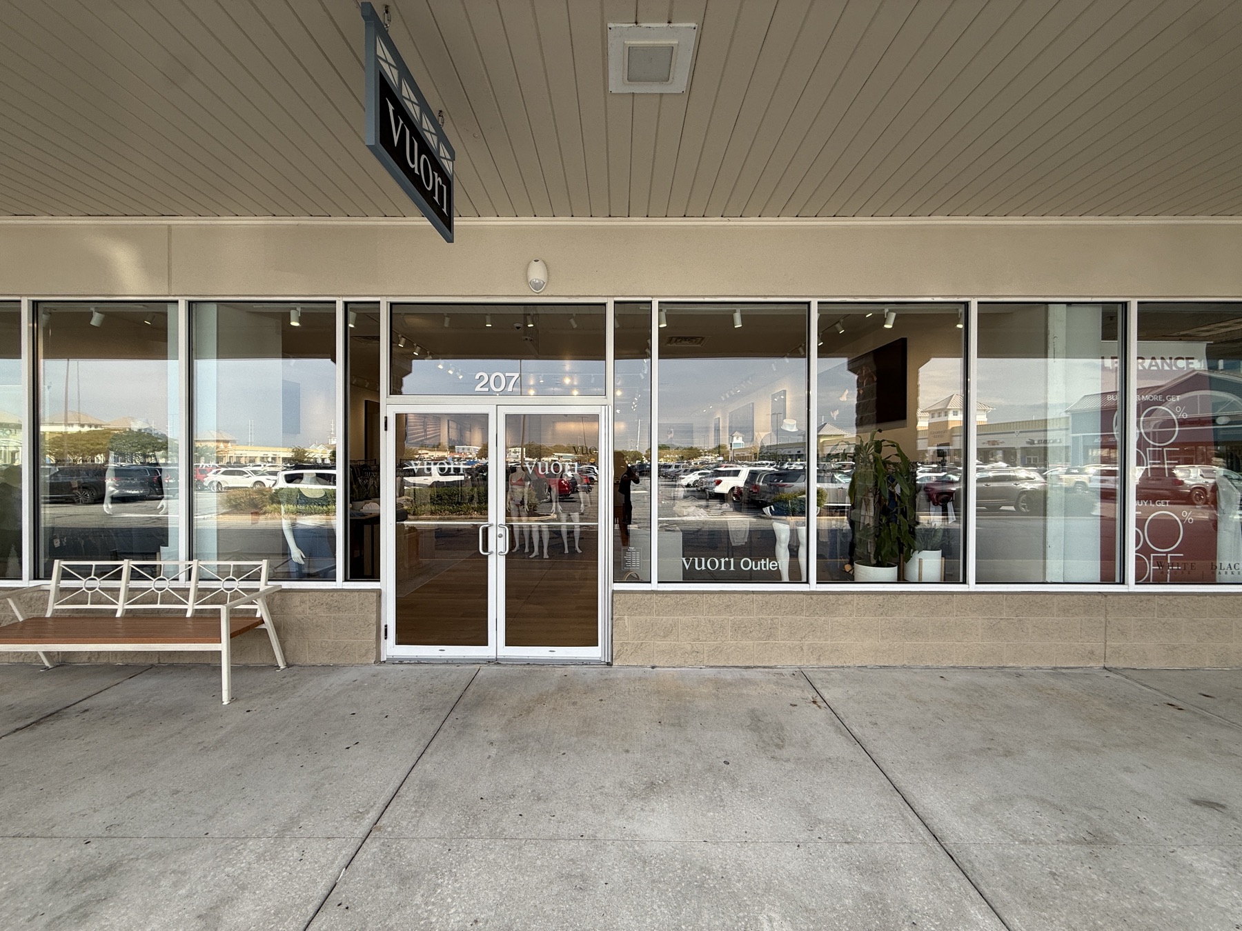 Storefront with hanging blade sign and full window graphics at a retail center