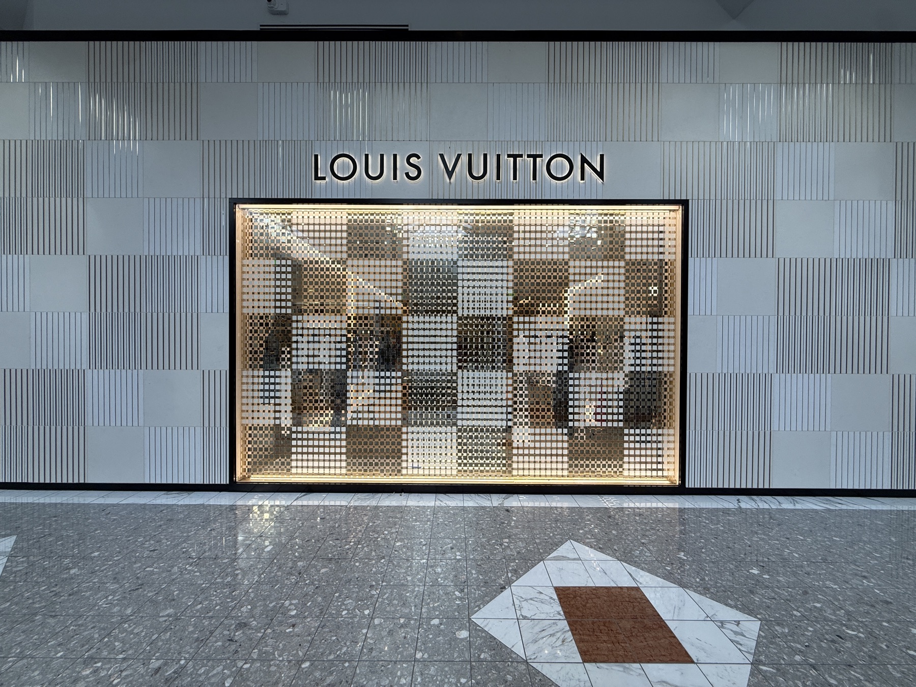 Backlit architectural mesh graphic and halo-lit letters on a mall facade