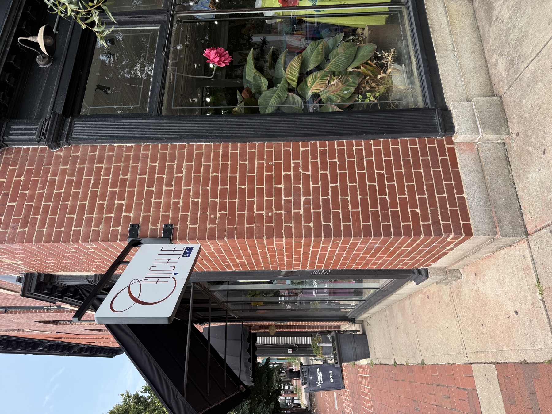 Projecting blade sign mounted on a brick storefront pier